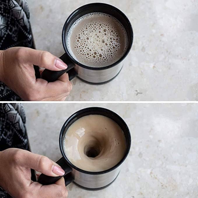 A person holding the mug with coffee stirring in it.