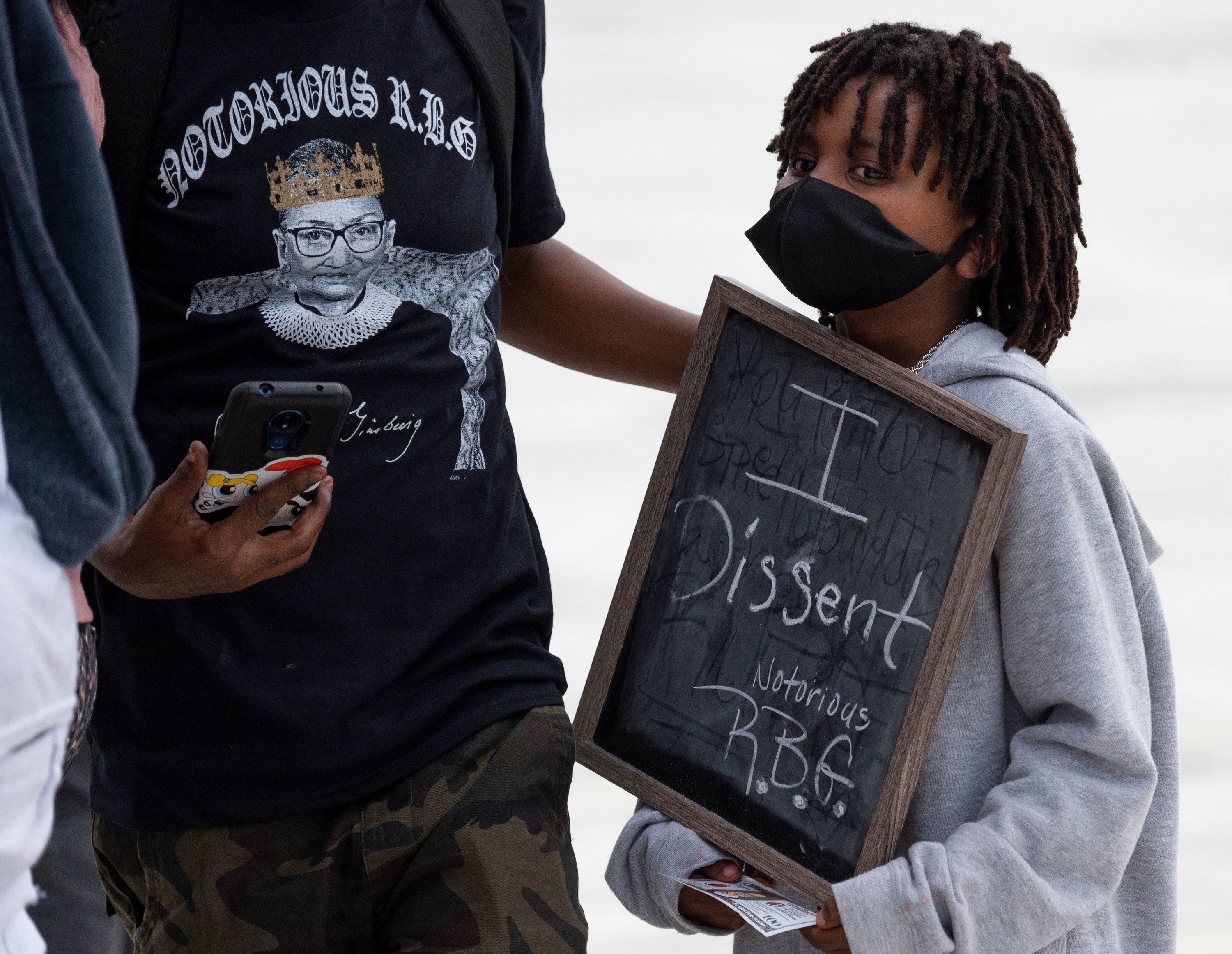 A boy carries a sign that says I Dissent