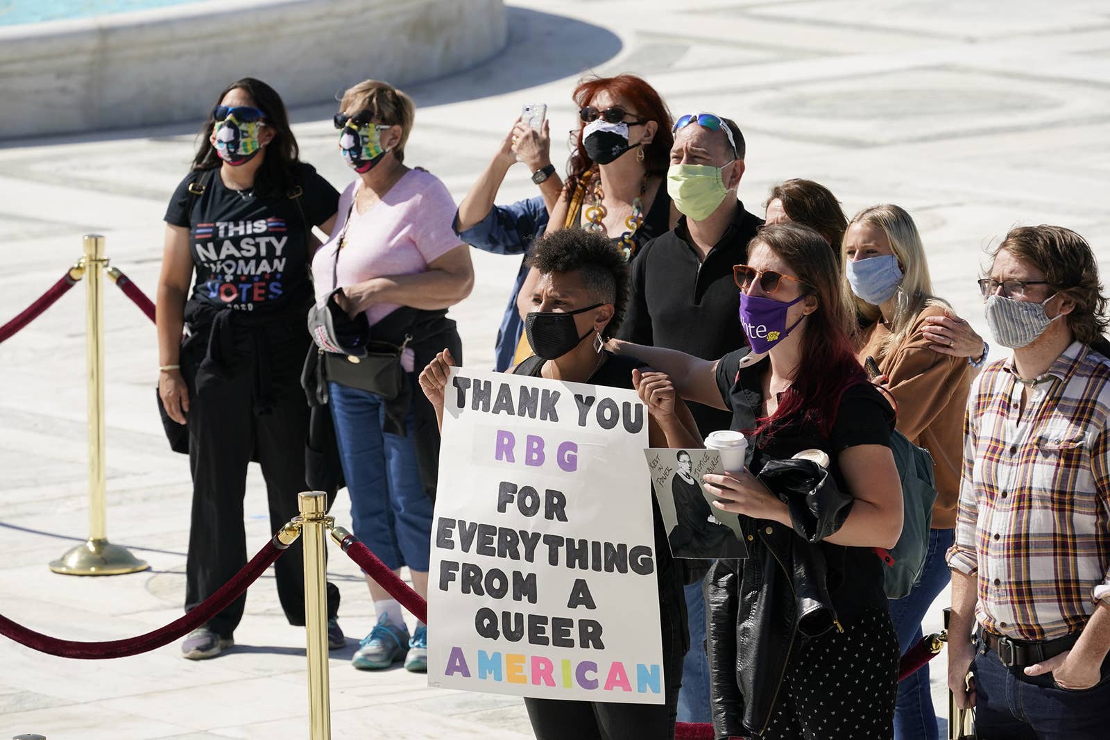 A young person holds a sign saying Thank you RGB for everything from a queer american