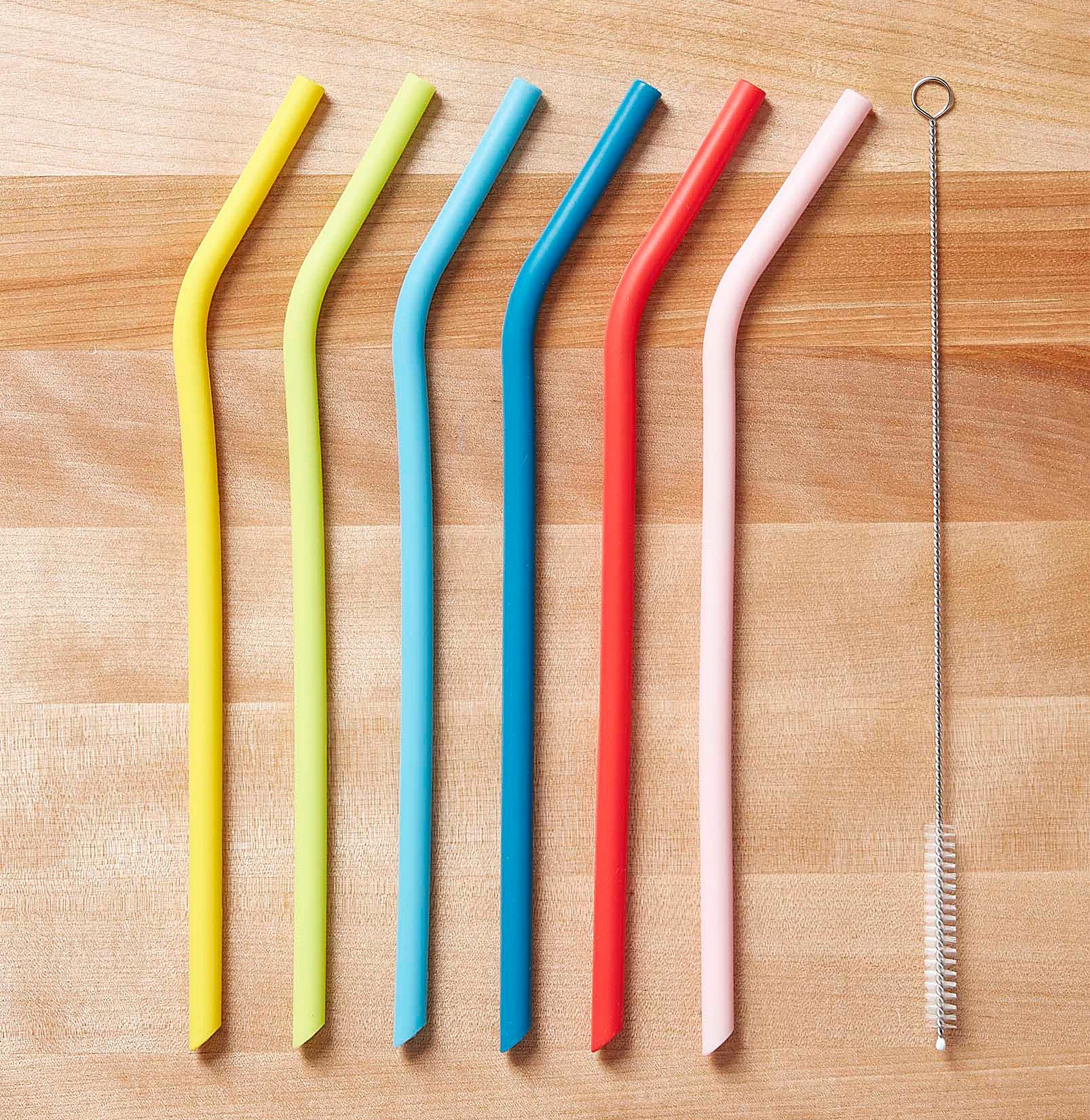 The six straws and their cleaning brush on a table
