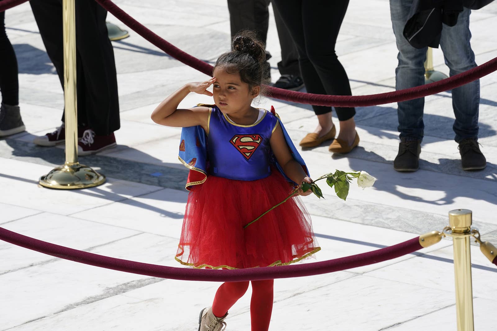 A girl dressed in a Supergirl costume pays her respects at the casket