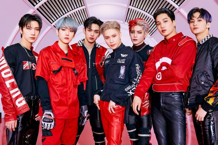 SuperM members Mark, Taeyong, Lucas, Taemin, Kai, Ten, and Baekhyun pose in matching red and black leather ensembles