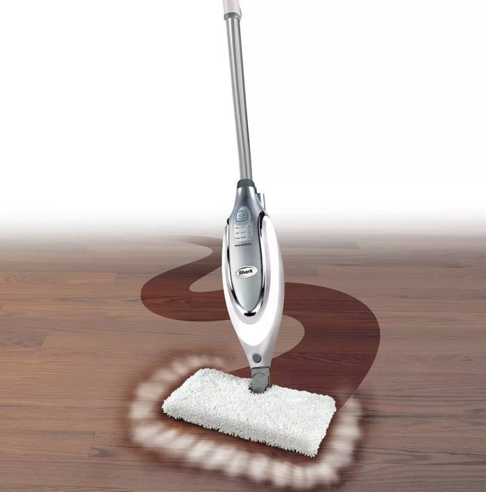A silver steam mop is being used on a wooden floor to show how it cleans