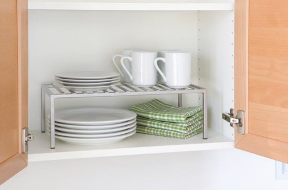 The expandable kitchen shelf organizer being used to hold cups and plates