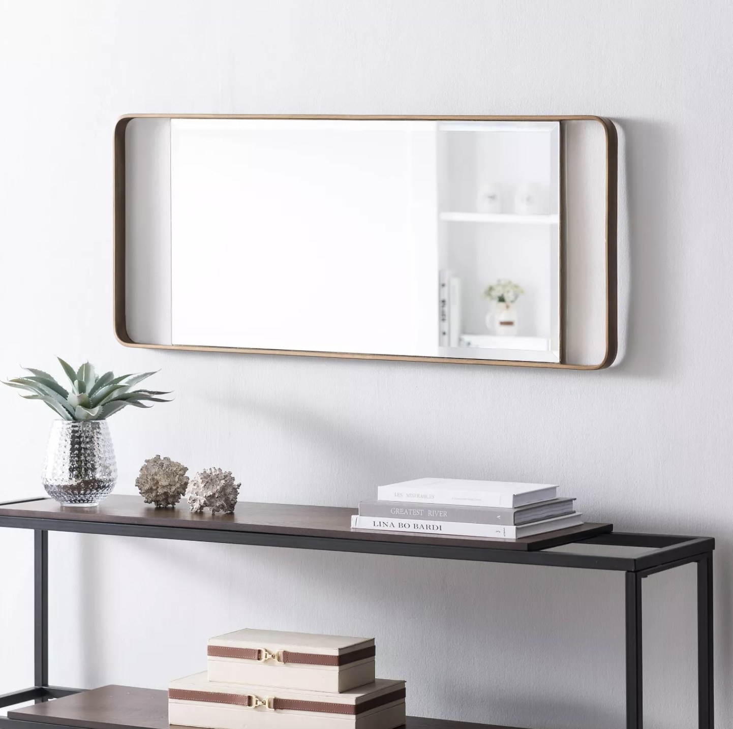 A rectangular leaning mirror with a gold finish hung up on a wall in a home