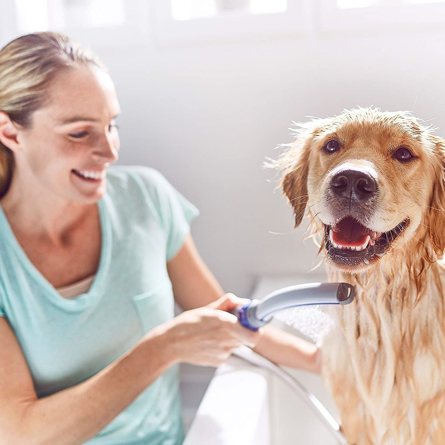 The curved bath wand being used in a bathtub to wet a dog