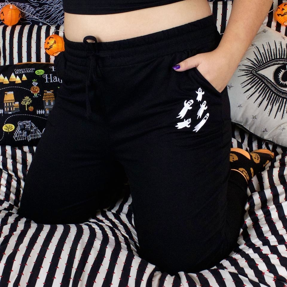 model wearing black sweatpants with white ghost logo