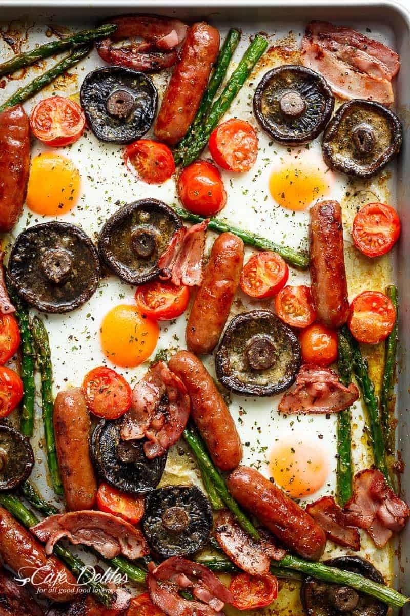 A sheet pan filled with roasted vegetables and meats, with runny baked eggs placed throughout.