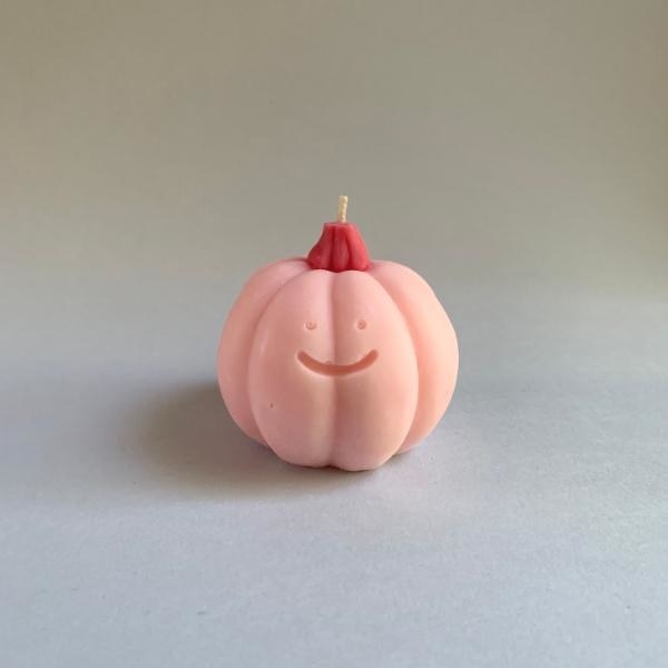 pink pumpkin shape candle with a happy face on it