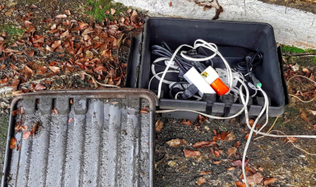 Reviewer shows black weatherproof connection box with power strips inside on the ground