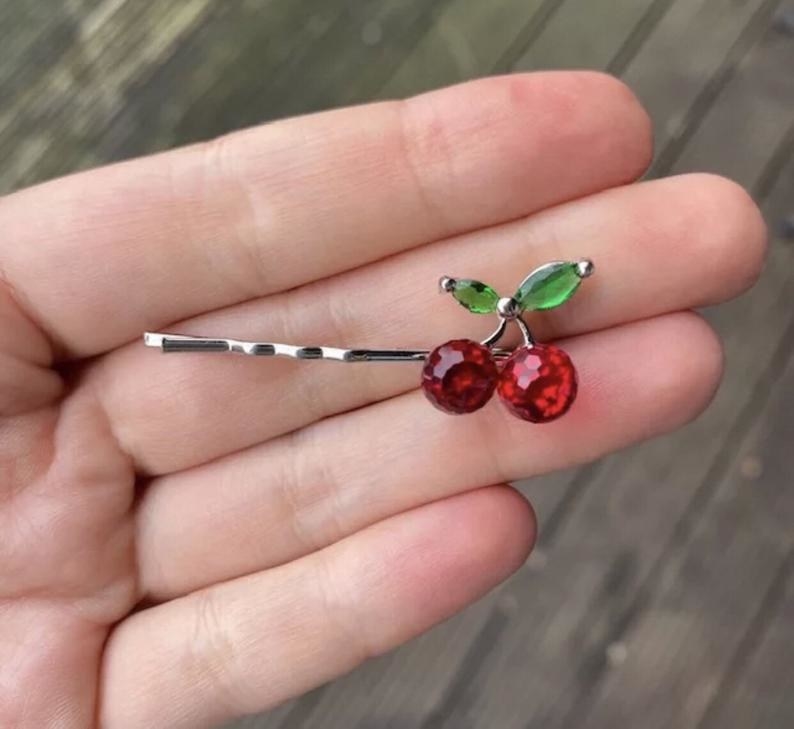 a hand holding the cherry barrette 