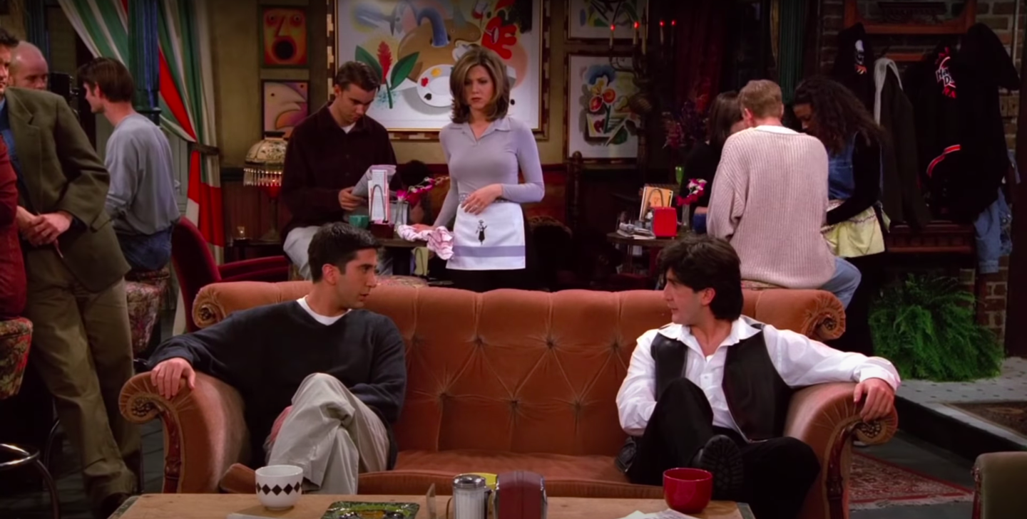 Ross and Russ (both played by David Schwimmer) face each other on the Central Perk couch while Rachel looks on