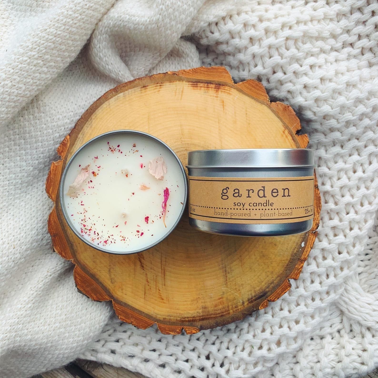 White wax candle with silver tin and pink dried flower petals embedded in the wax