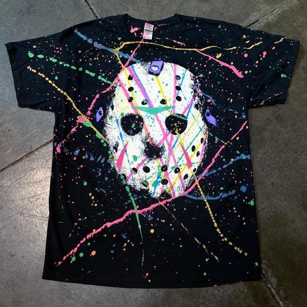 black shirt with Friday the 13th Jason Vorhees mask on it with splatter paint pattern on top