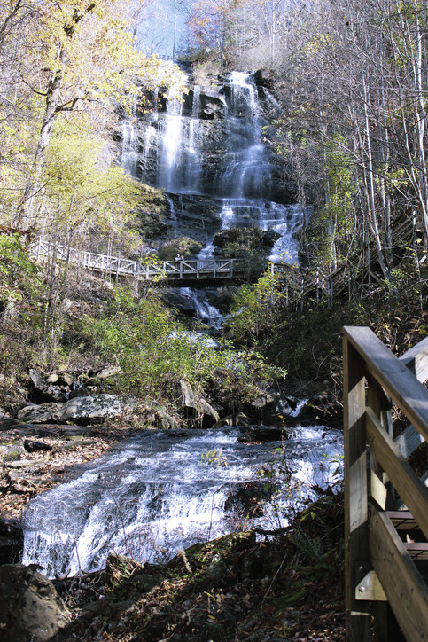 A footbridge winds around a towering. rocky waterfall
