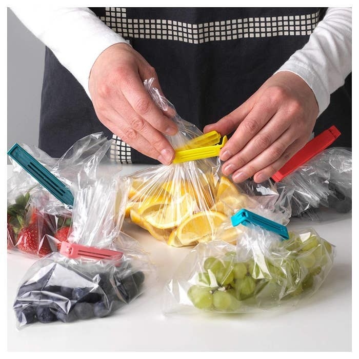 A person using the baggie clips to seal bags of food.