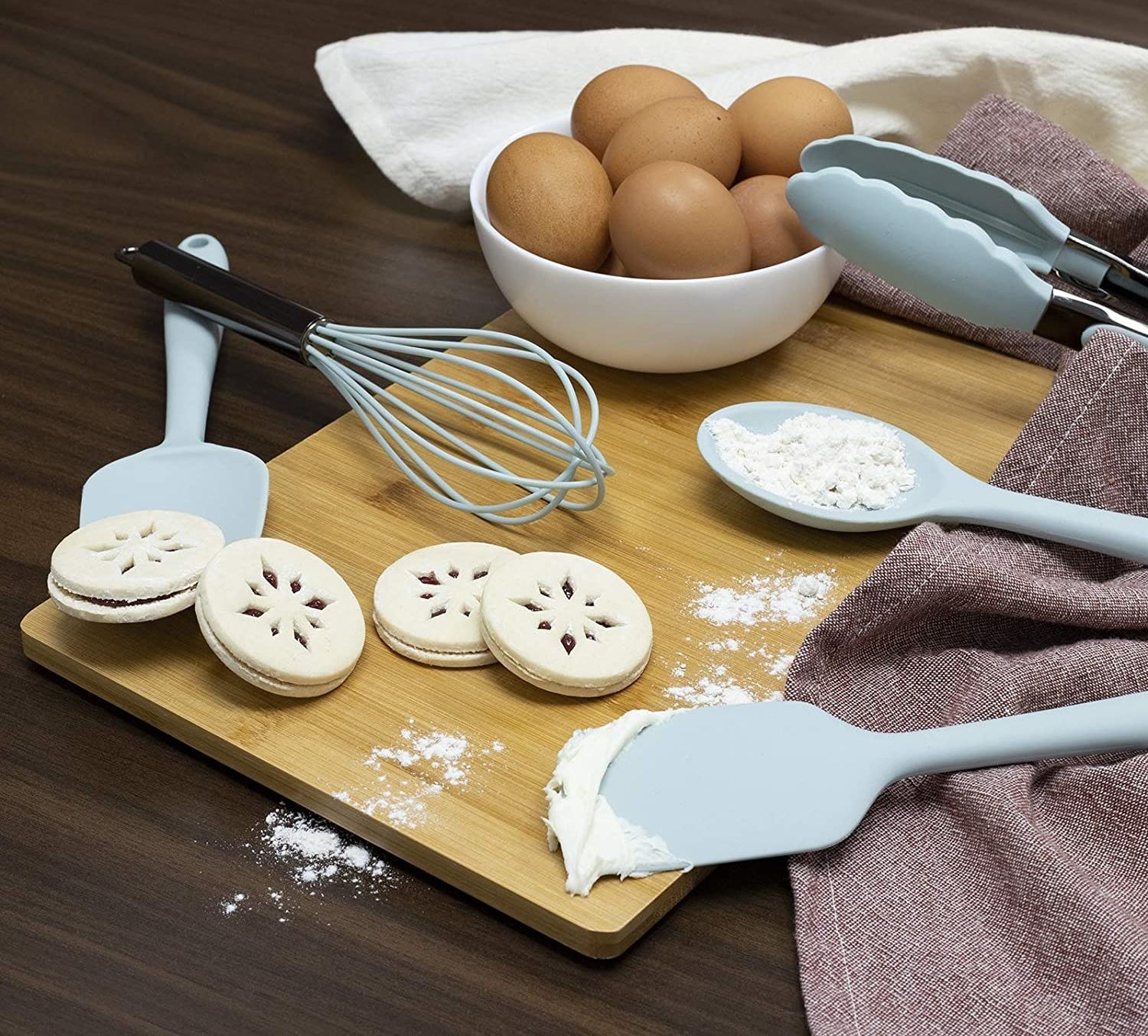 A set of mini utensils laid out with cookies on a cutting board