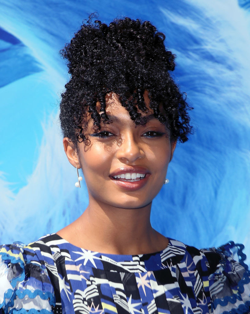 Yara smiling with her hair up in dangling earrings and a patterned dress