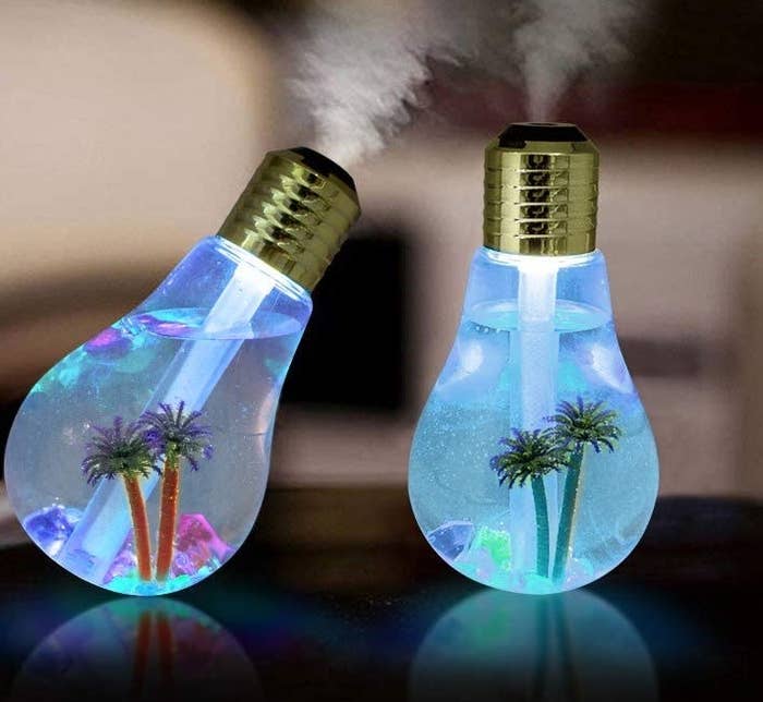Two llghtbulb shaped humidifiers giving off steam with little palm trees in them