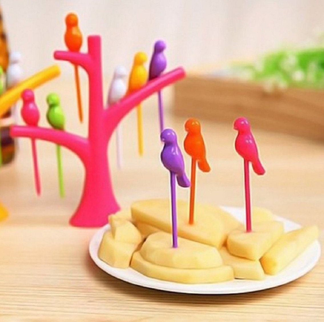 Fruit forks placed inside the tree-shaped stand they come with, while three of them are poked into food.