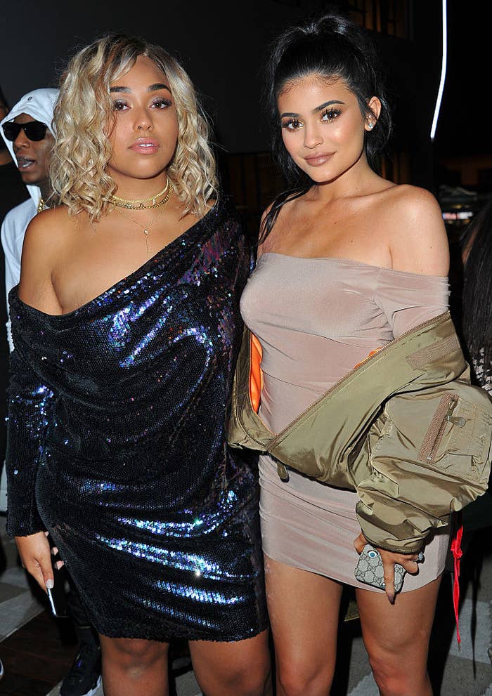 Jordyn wearing a dark, shiny dress and Kylie wearing a neutral low cut dress with a puffy jacket