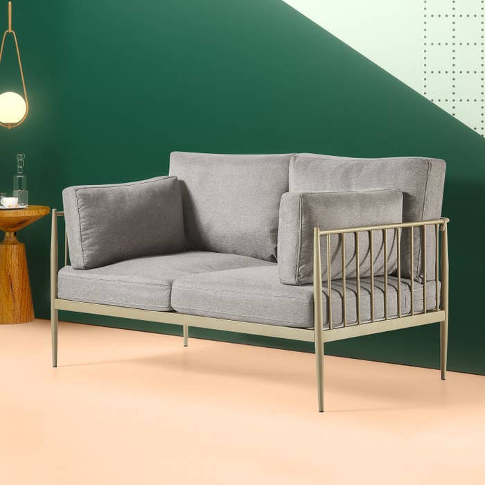 The grey couch with a gold frame in front of a wall 