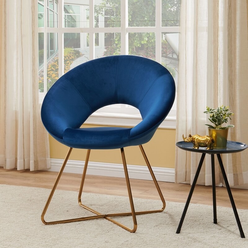 A blue velvet round chair with gold metal legs