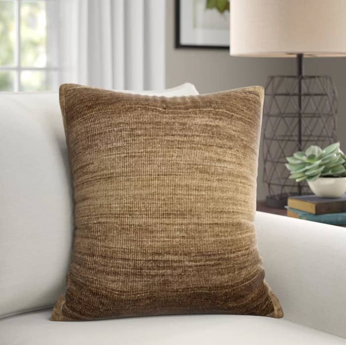 The throw pillow in neutral/brown on a white couch