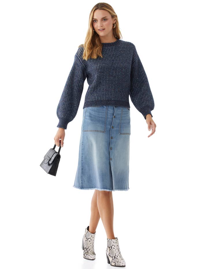 Model wears denim boot skirt with sweater and booties.
