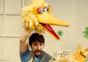Caroll Spinney holding the big bird mask above his head