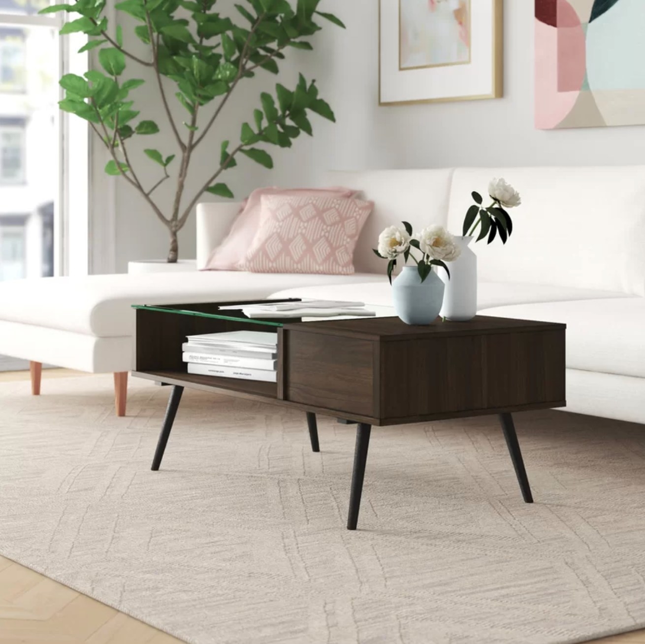 The coffee table in dark walnut holding books and a vase of flowers