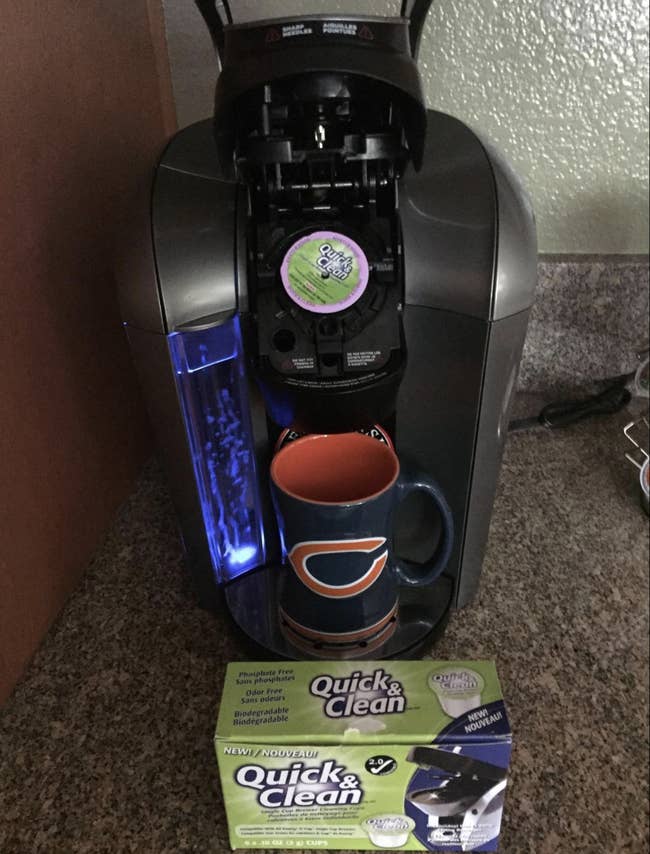 A package of cleaning K-cup in front of a Keurig machine and in the machine's pod
