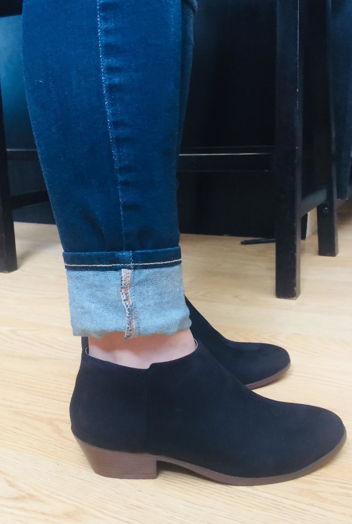 Reviewer wearing the ankle booties in black with brown heel and sole. 