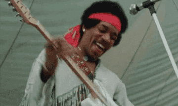 Jimi Hendrix happily playing the electric guitar at the Woodstock festival
