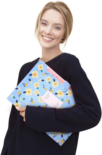 Model carrying the large blue floral folder with divider tabs