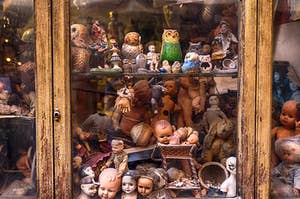An old cabinet filled with creepy old dolls and figurines 