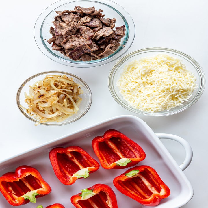 Cheese, onions, steak, and bell peppers on a tabletop.