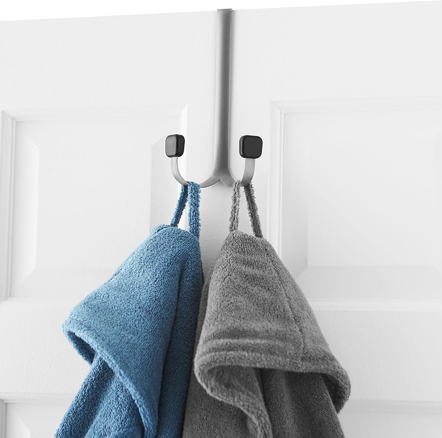 A hook hanging from the top of door with two robes hanging from it