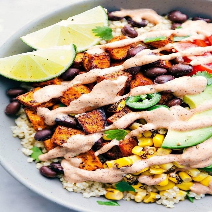 A taco bowl with sweet potato, corn, rice, black beans, and a creamy dressing.