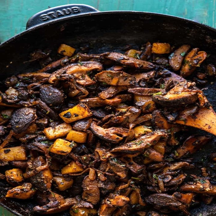 Assorted mushrooms cooking in a skillet.