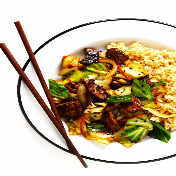 A bowl of stir-fried beef and cabbage over rice with chopsticks on the side.