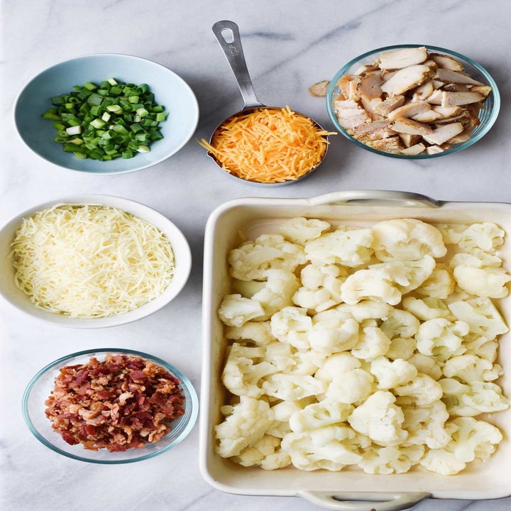 Cauliflower florets, cheese, sliced chicken, bacon bits, and scallions in little bowls.