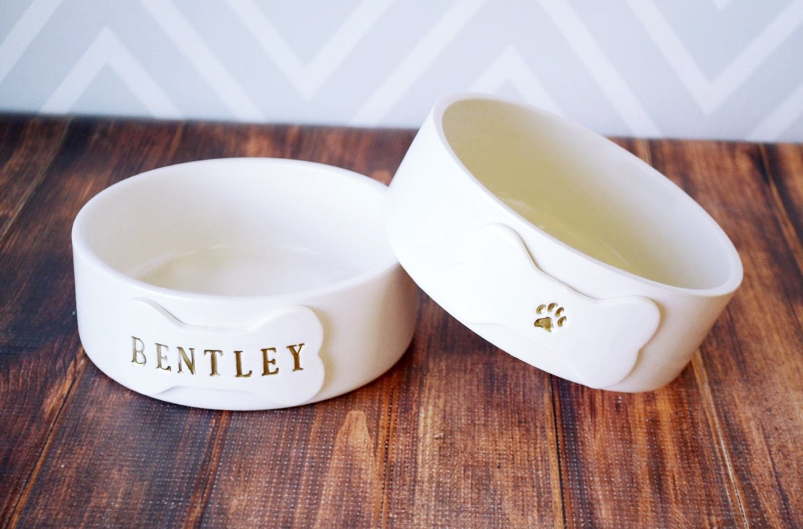 White ceramic bowls with a dog bone design on the front and the name &quot;Bentley&quot; on one bone and a paw print on the other