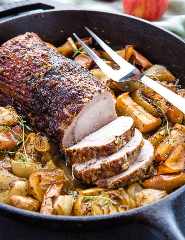 A skillet filled with apples, onions, and sliced pork tenderloin.
