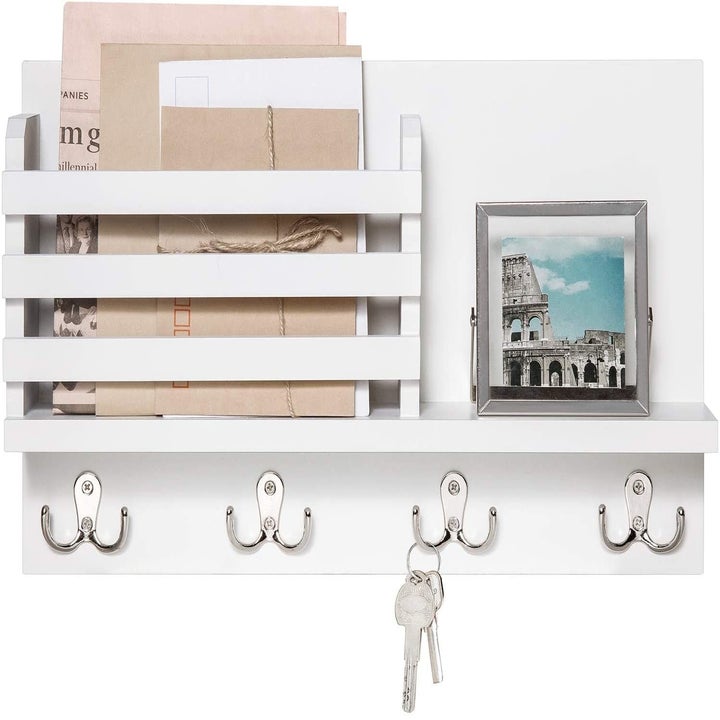 The product mounted to the wall holding keys, mail, and a picture