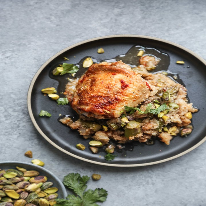 A plated crispy chicken thigh over cauliflower couscous.