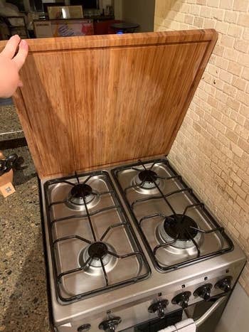 a hand lifting the cover showing the stove-top underneath