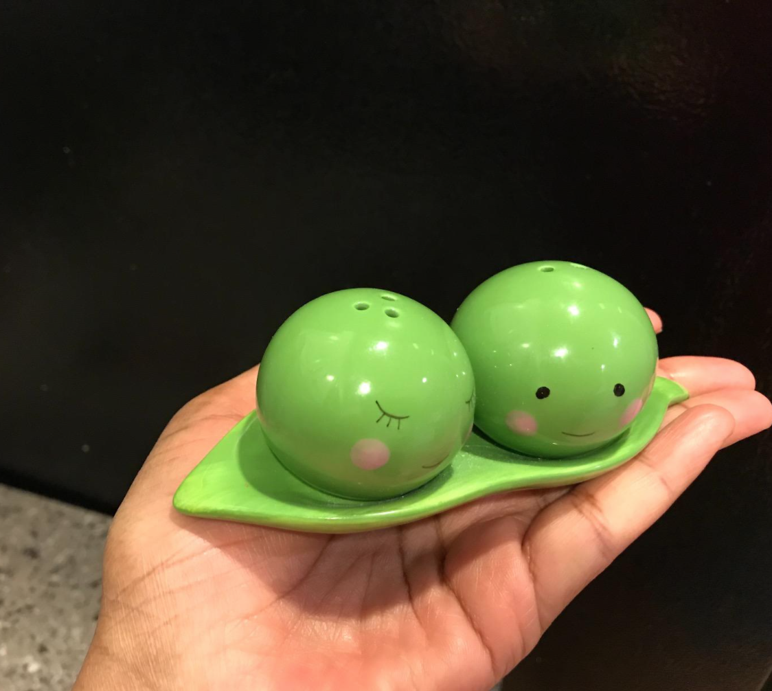 Cute ceramic peas that are salt and pepper shakers that rest on a matching pod holder