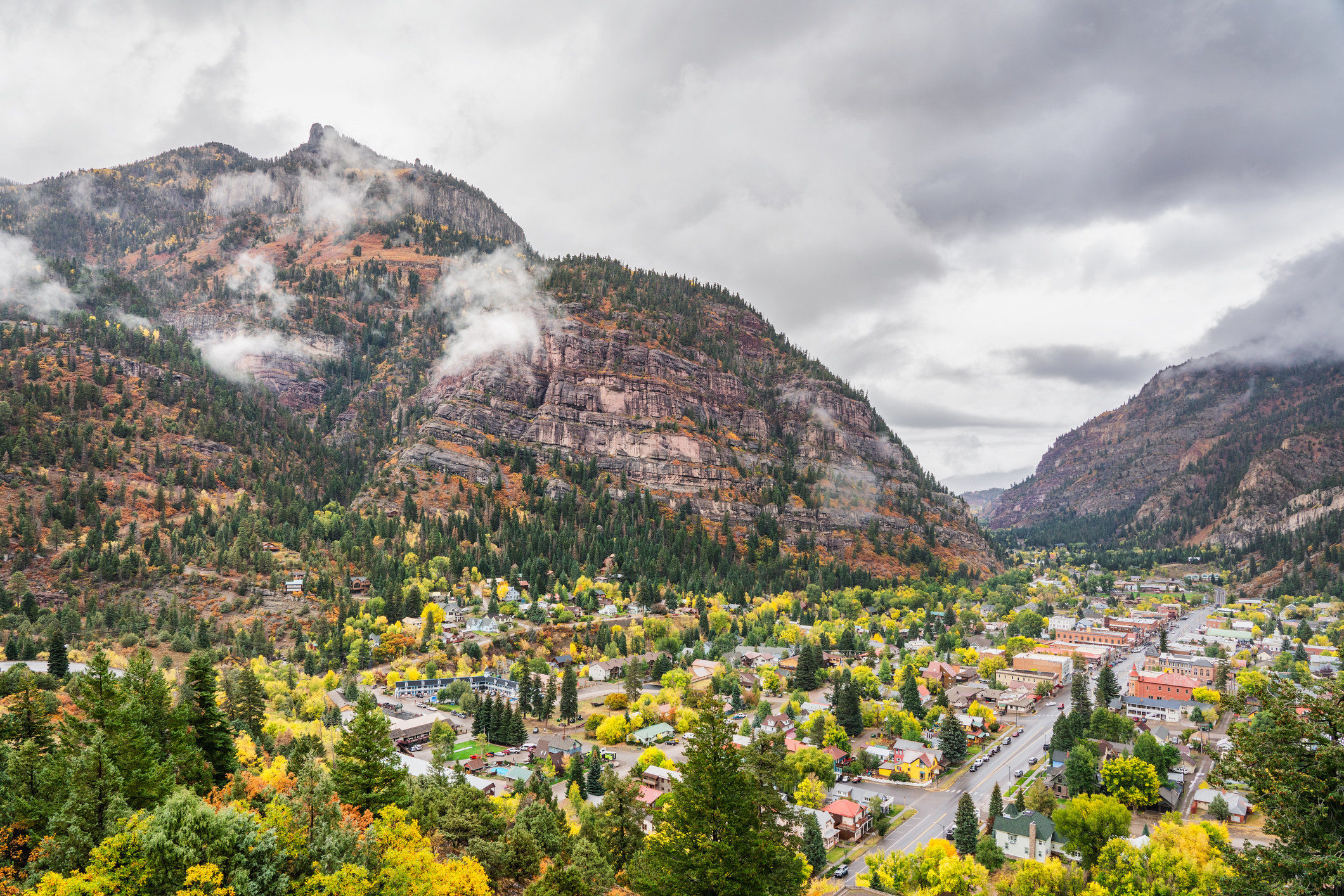 Overhead view of a small town nestled between mountains on a cloudy, fall day