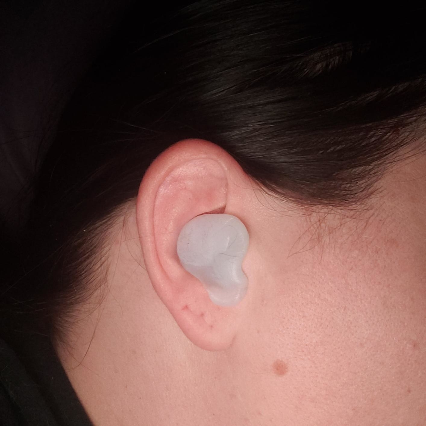 A reviewer&#x27;s ear with the semi-opaque white, putty-like earplugs covering the opening